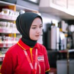 A young woman in hijab working as a cashier in a Palembang convenience store.