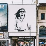 Busy Toronto street with shops, people, and large advertisement in urban setting.